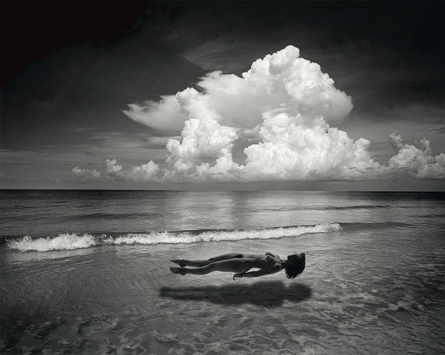Photomontage by Jerry UELSMANN showing a naked woman on levitation above the sea. There is a deep surrealistic feeling in this image.